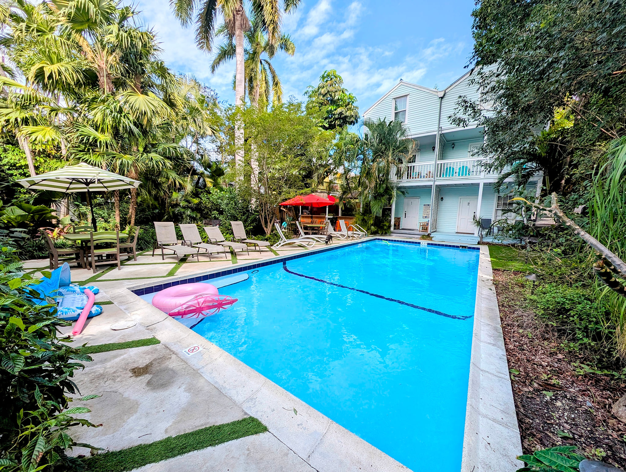 Tropical pool oasis with loungers, umbrellas, and shaded dining