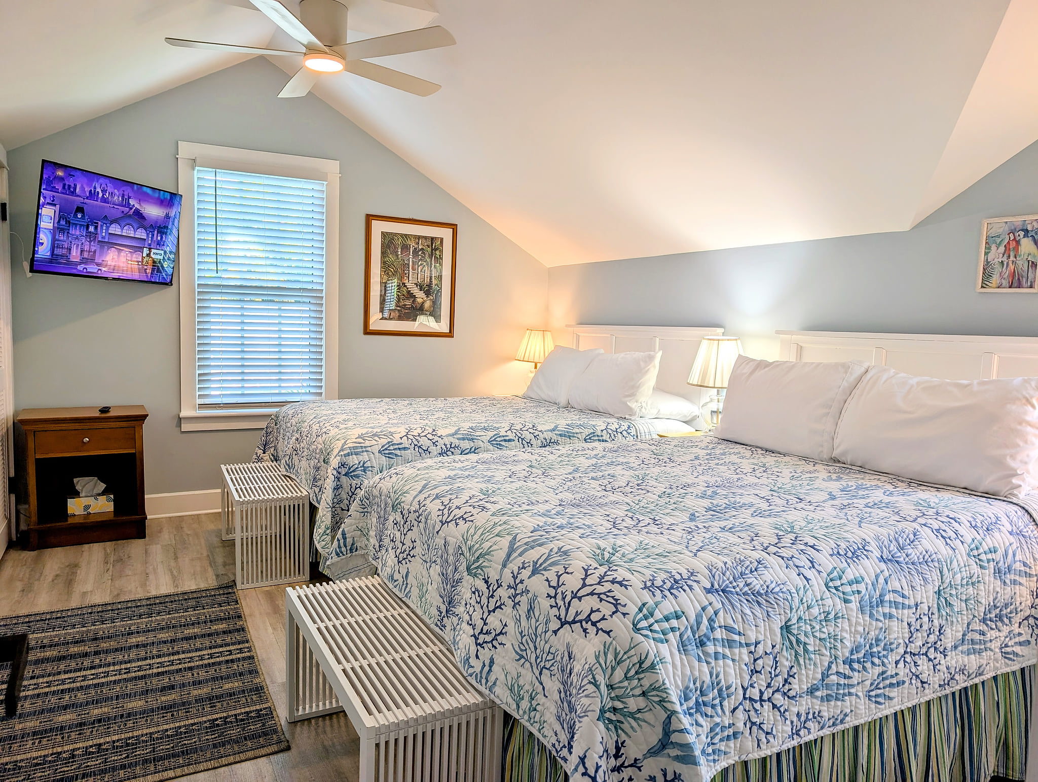 Cozy loft bedroom with two queen beds, TV, and coastal decor