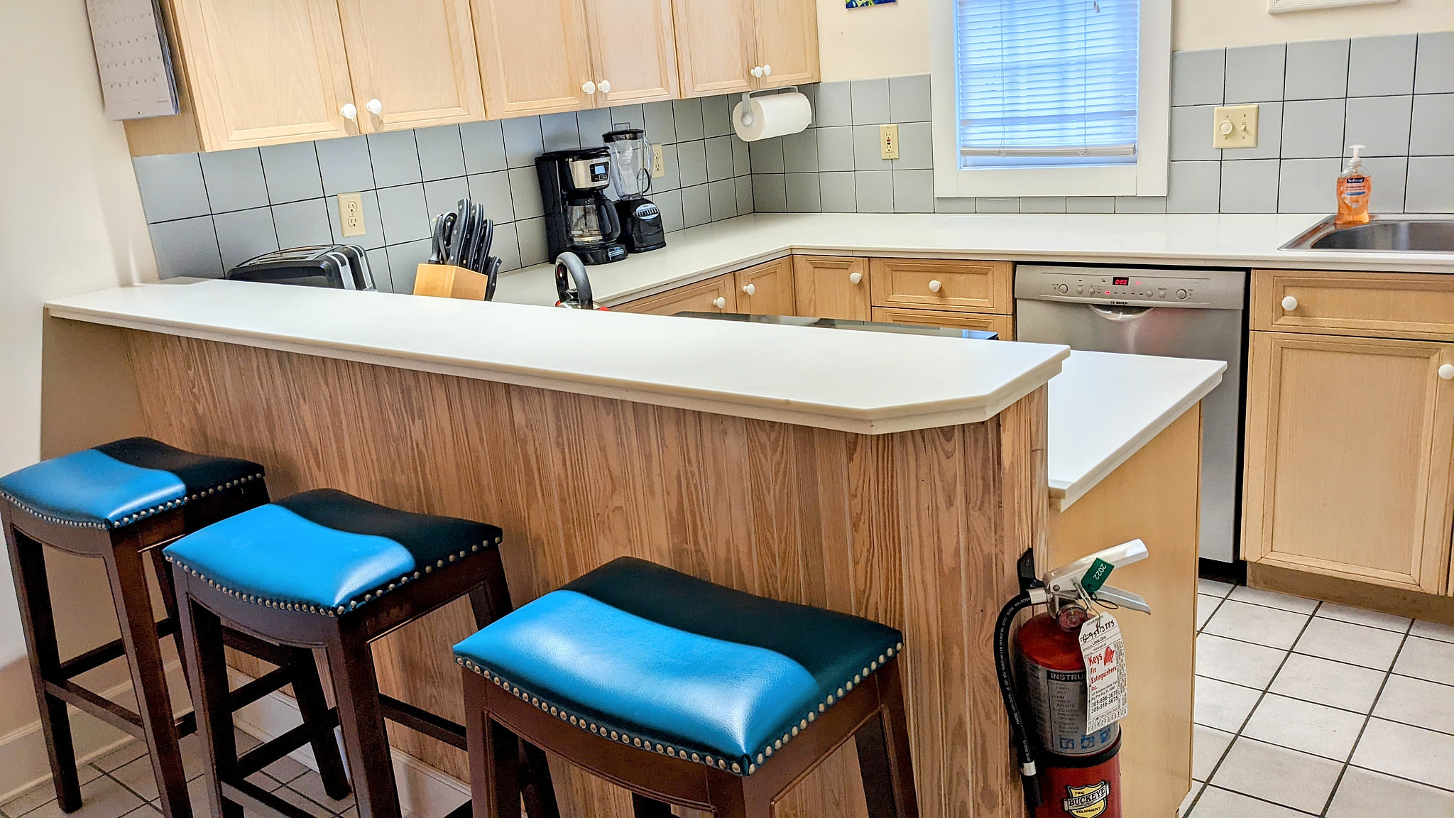 Bright U-shaped kitchen with bar seating, natural light, and full appliances