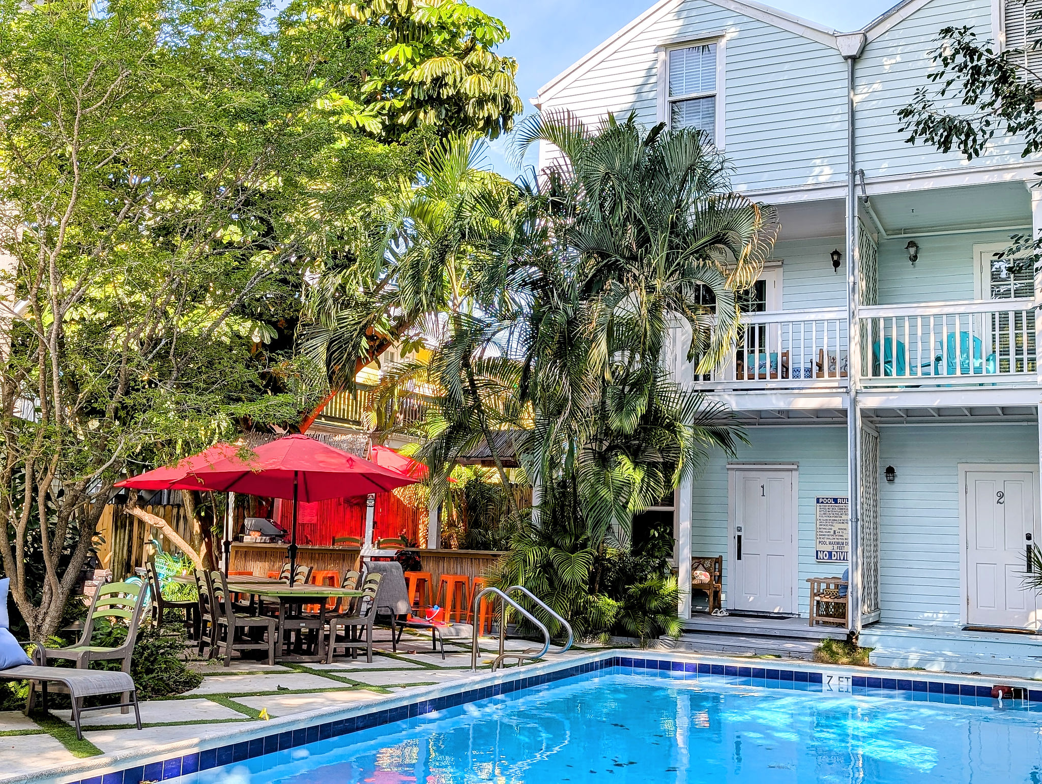 Tropical courtyard with pool, bar seating, and sunny balconies