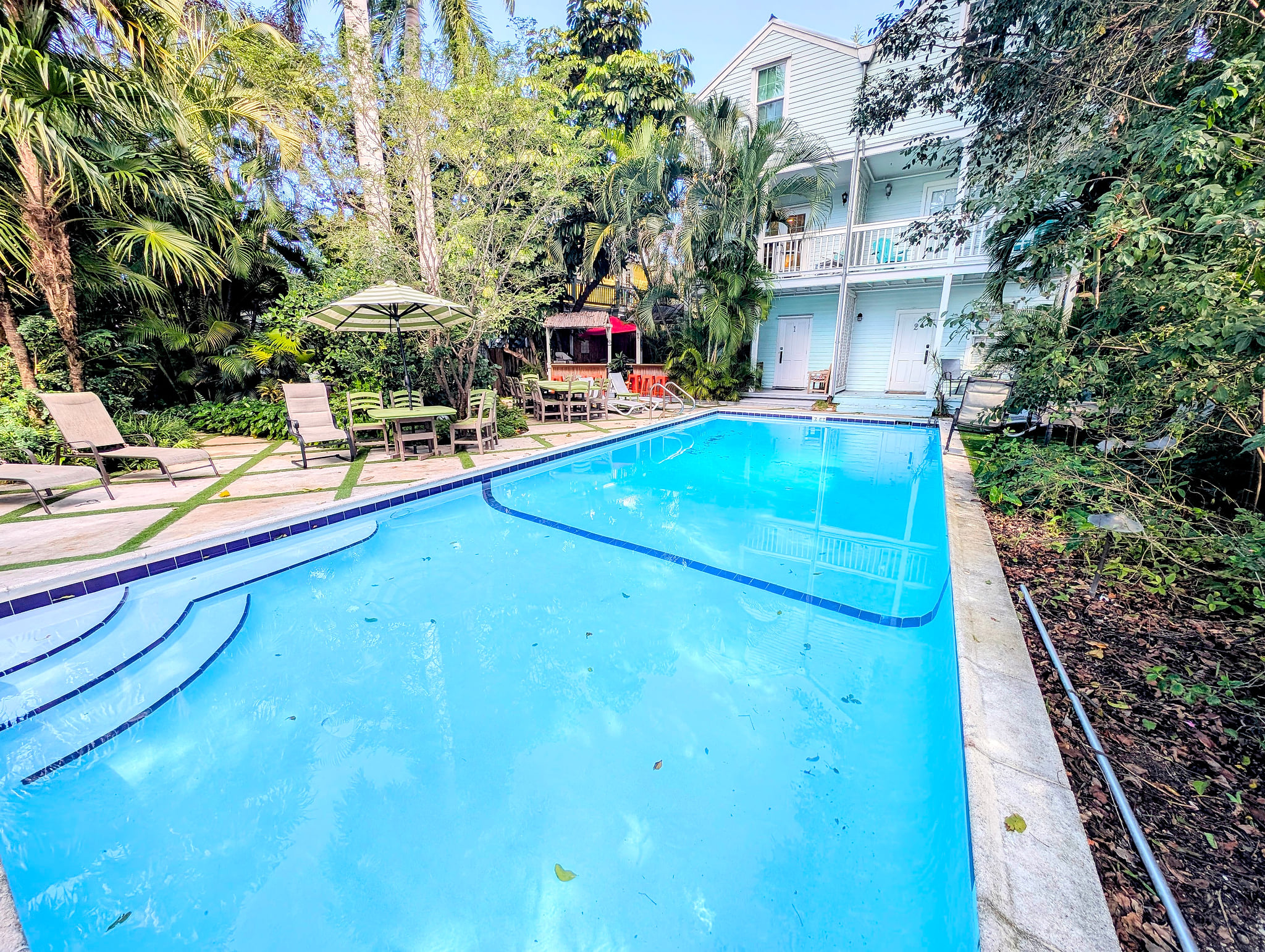 Tropical pool oasis w/ loungers, umbrellas and balcony views—private retreat.