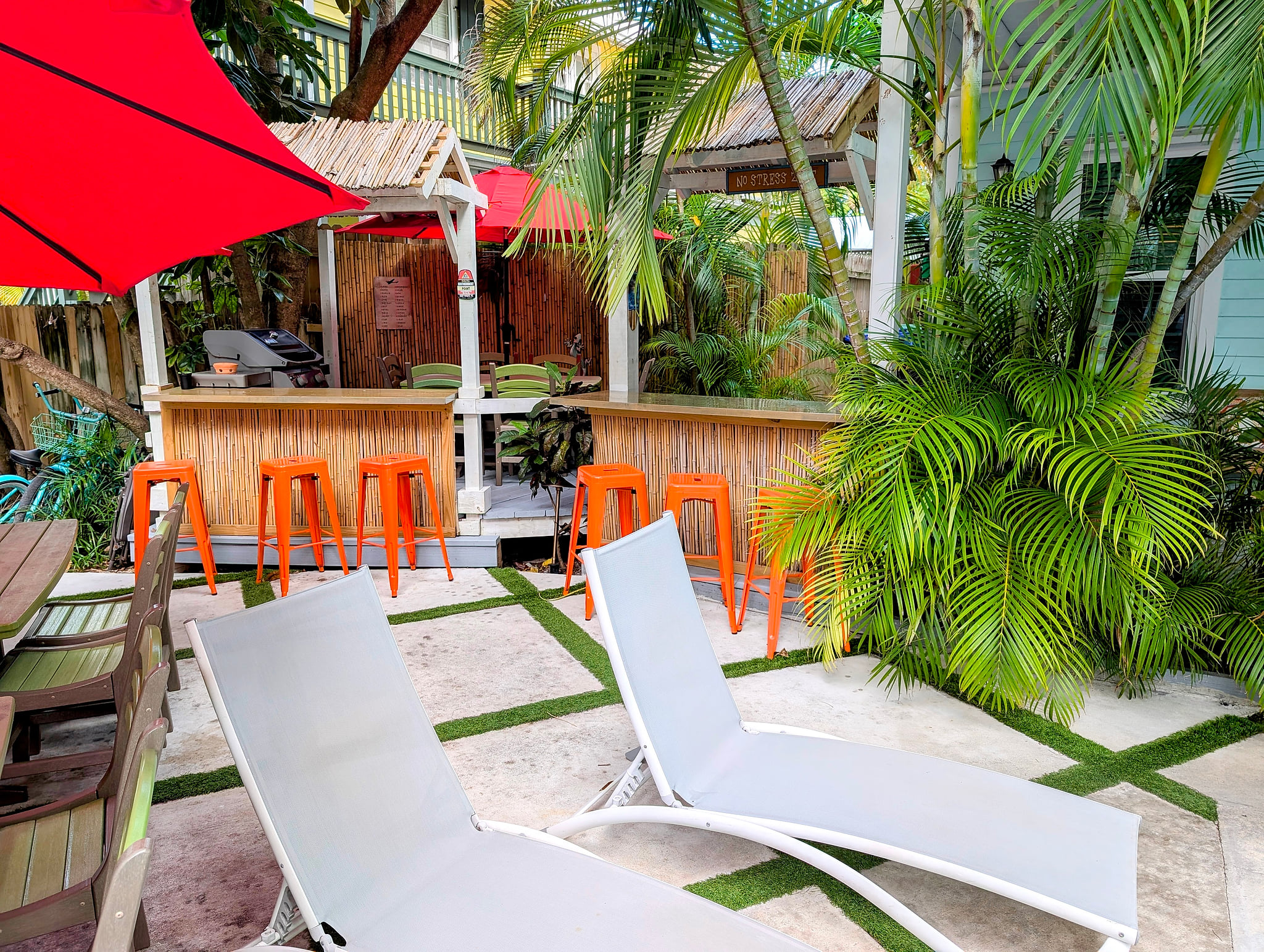 Tropical patio with tiki bar, grill, and sun loungers