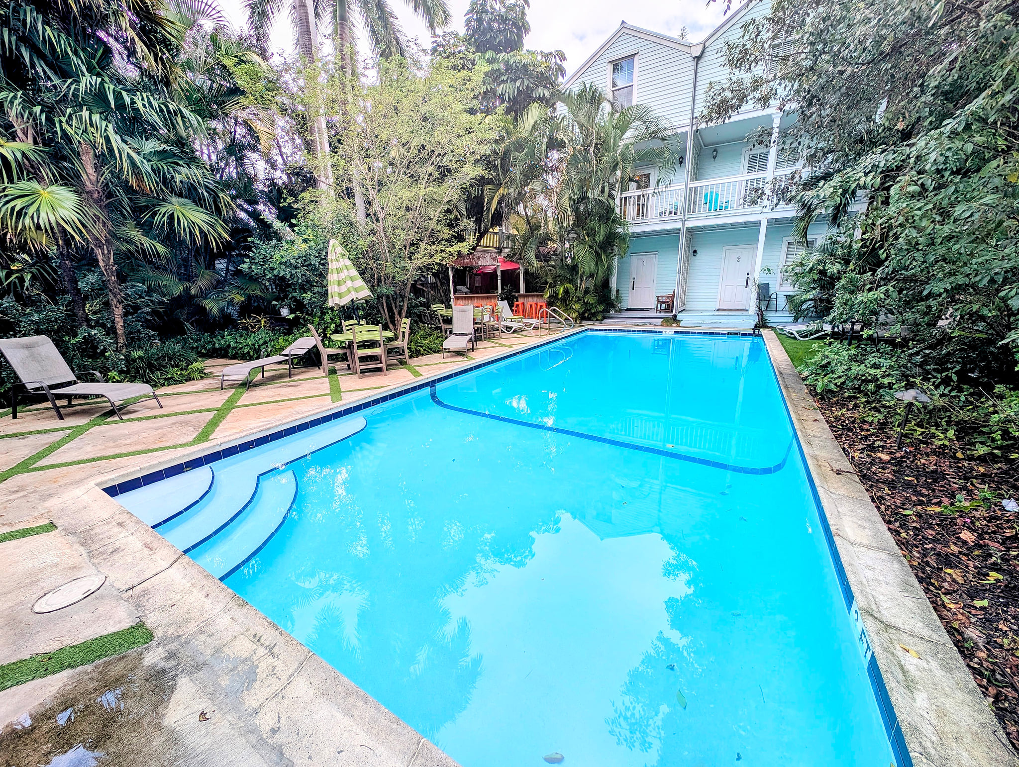 Tropical oasis: sparkling lap pool, loungers, and shaded patio by the suites
