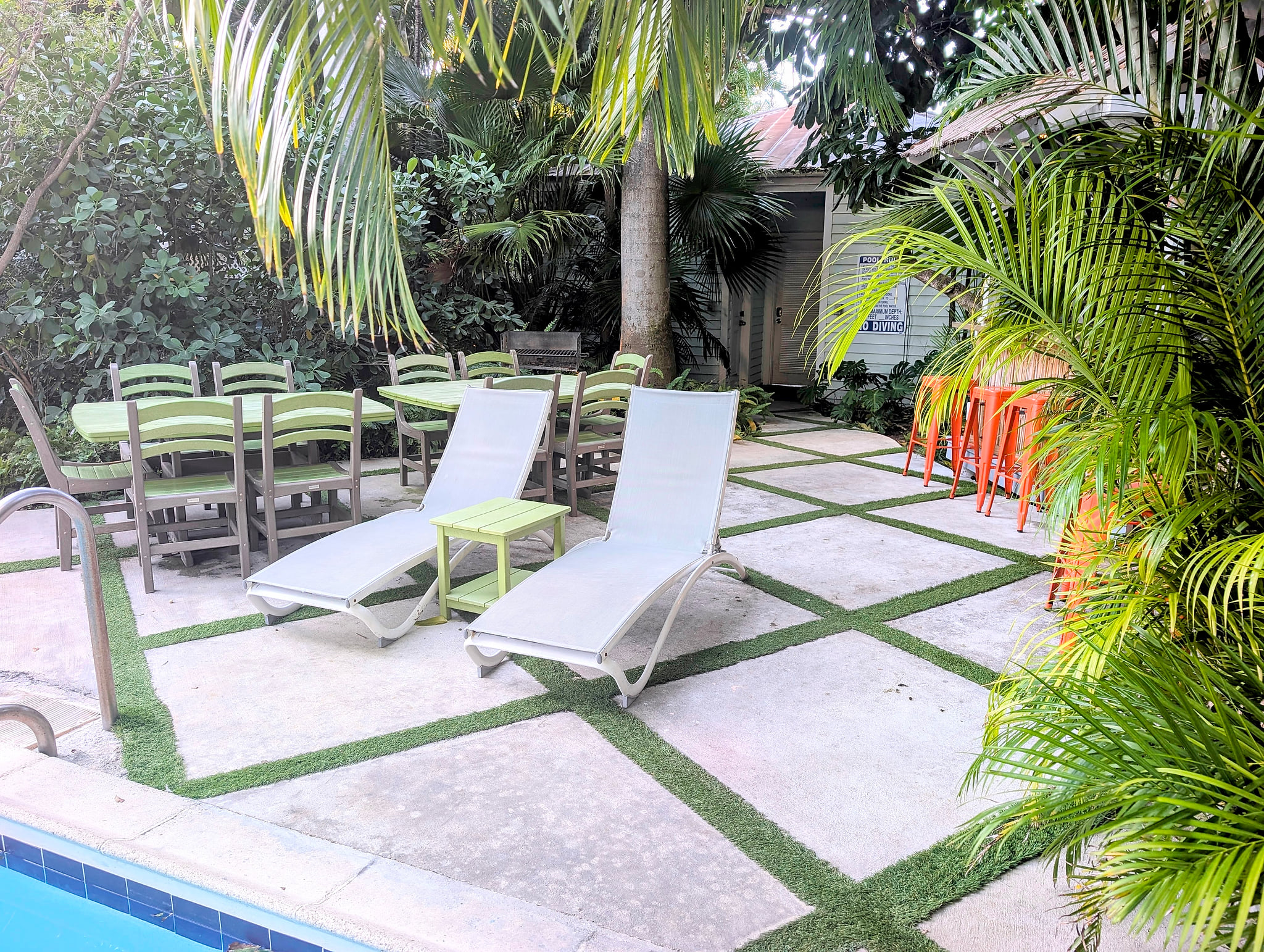 Tropical poolside patio with loungers, dining tables, and bar seating.