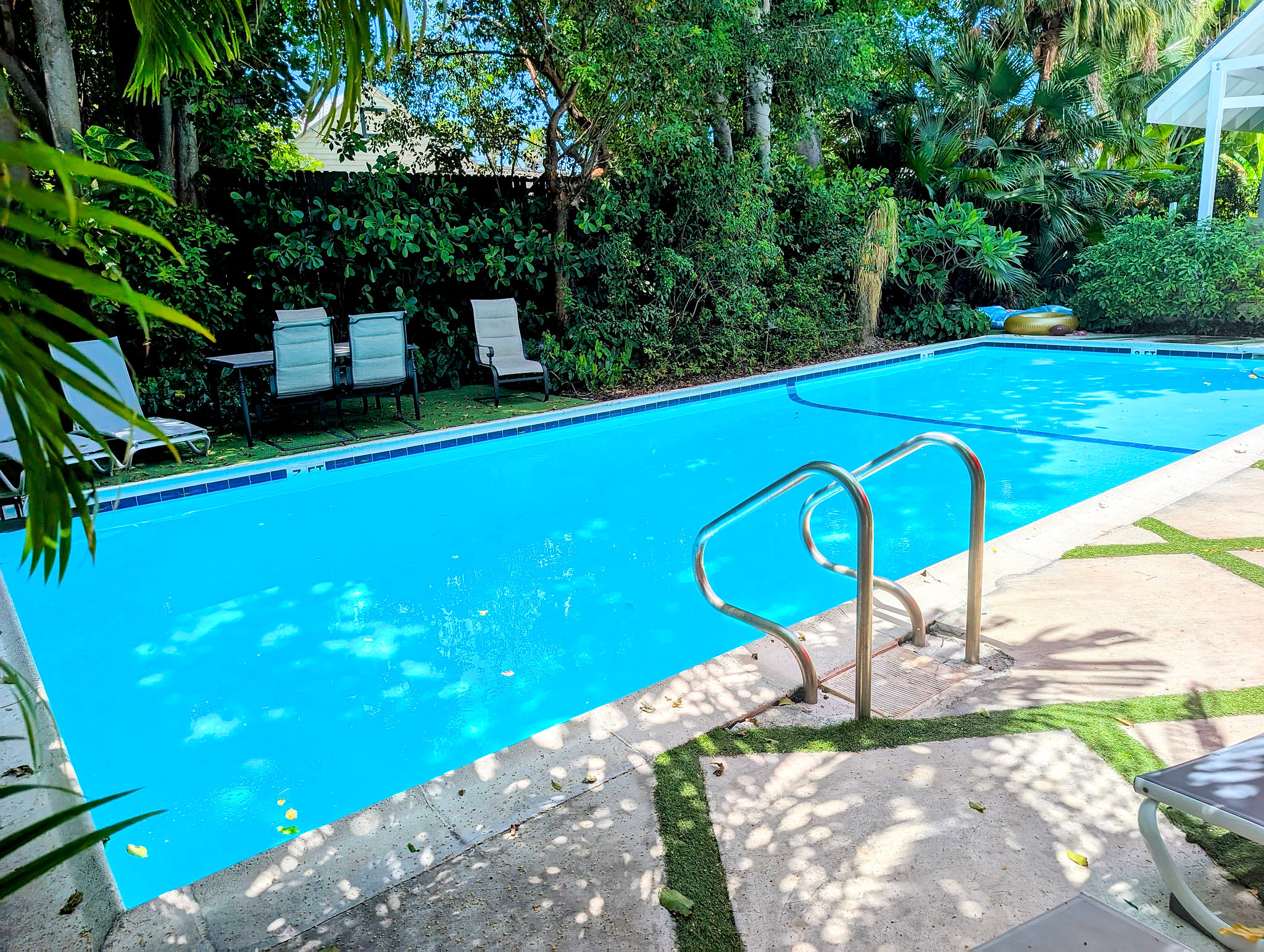 Private tropical lap pool with loungers, shade, and lush privacy