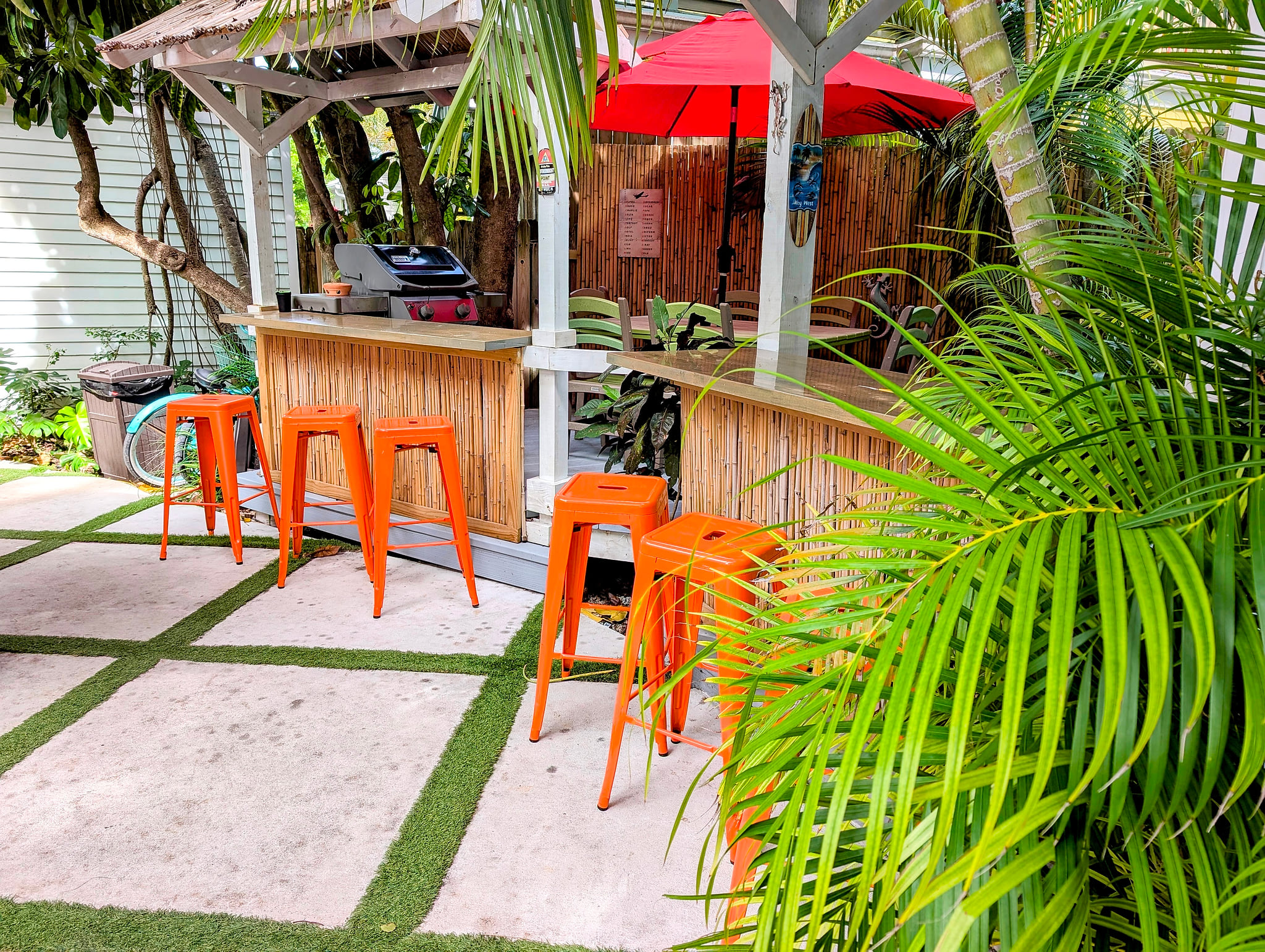 Tropical tiki bar with grill, bright seating, and lush palms
