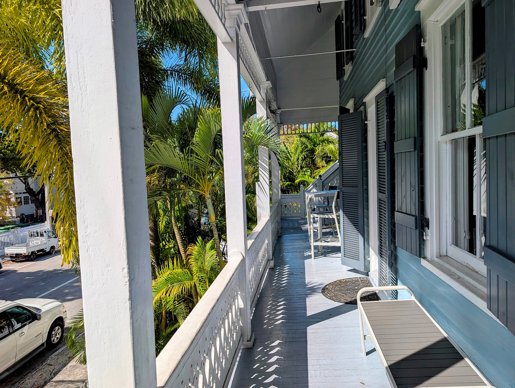 Sunny, shaded veranda amid palms—relax with street and garden views