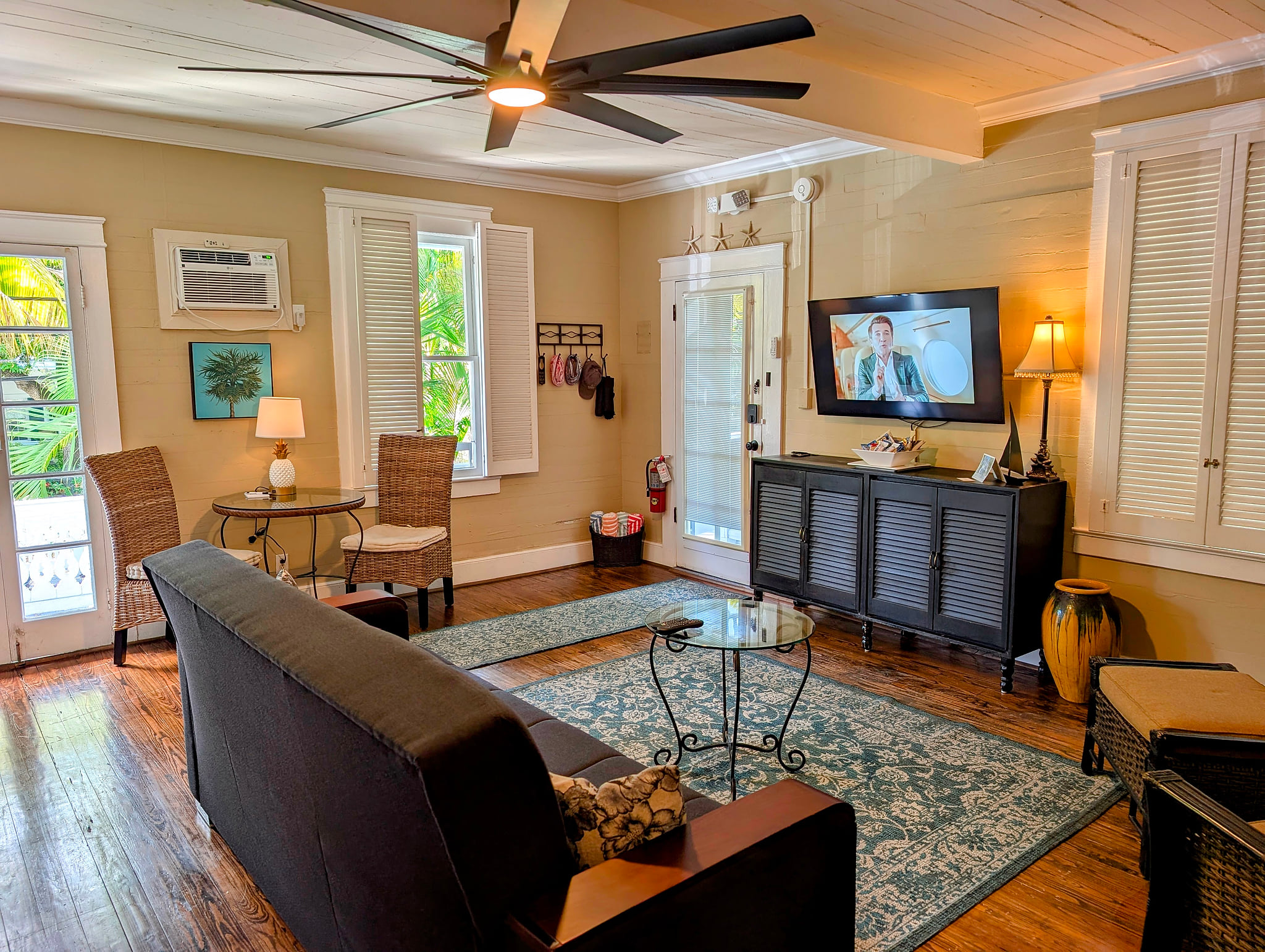 Sunny coastal lounge with porch access, AC, ceiling fan, and smart TV.