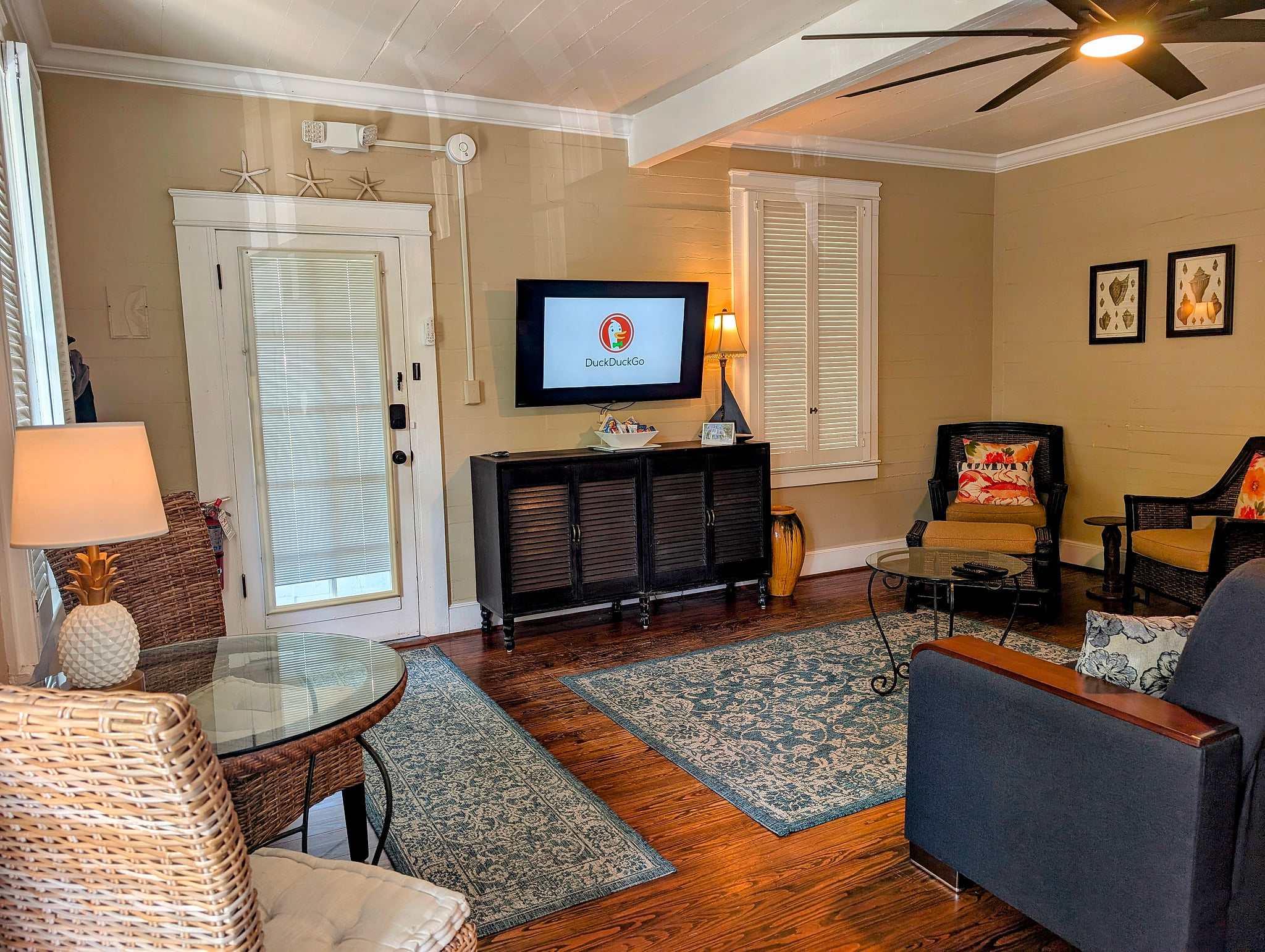 Sunny living room with hardwoods, TV, ceiling fan and coastal charm