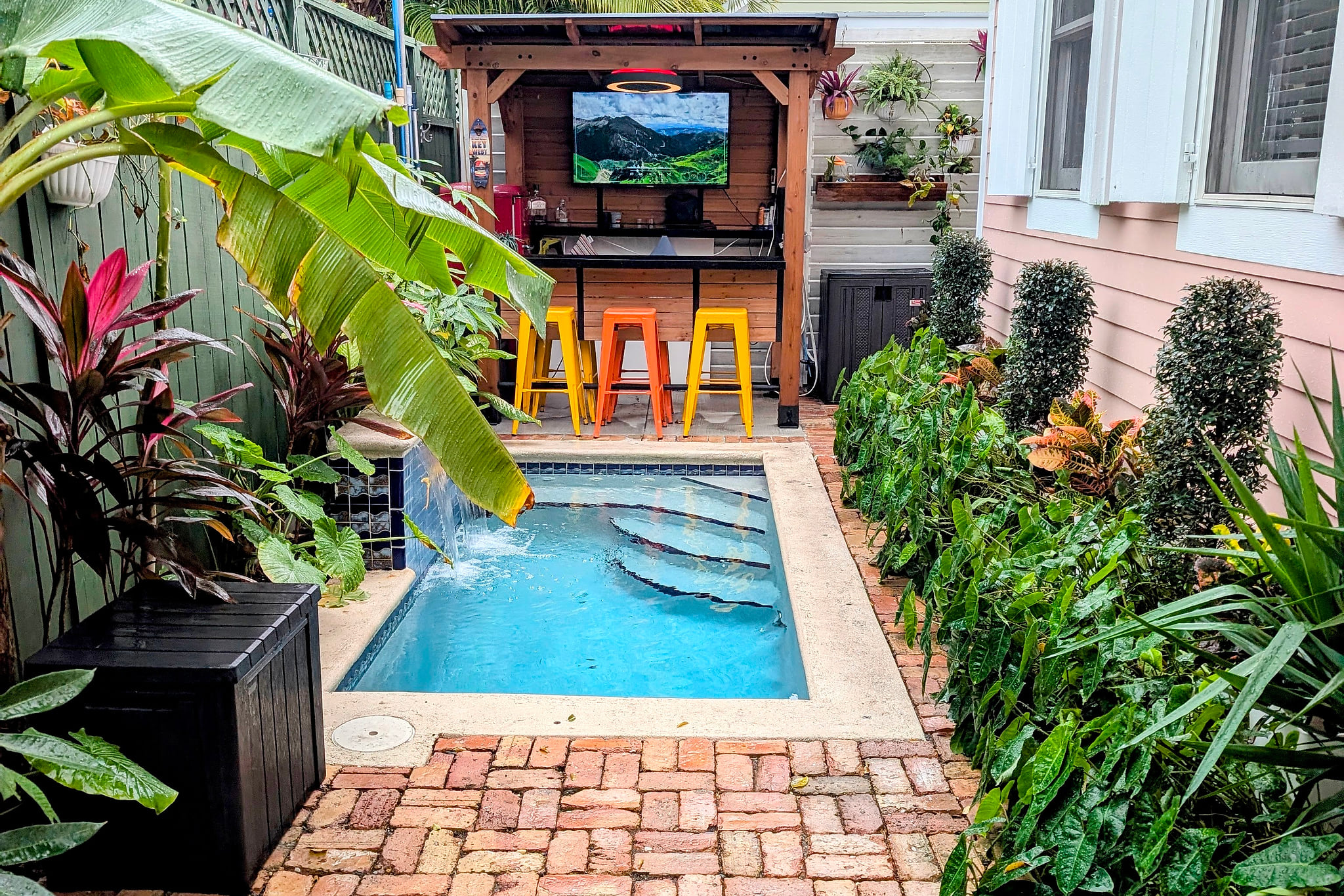 Tropical plunge pool oasis with bar, TV, and lush garden