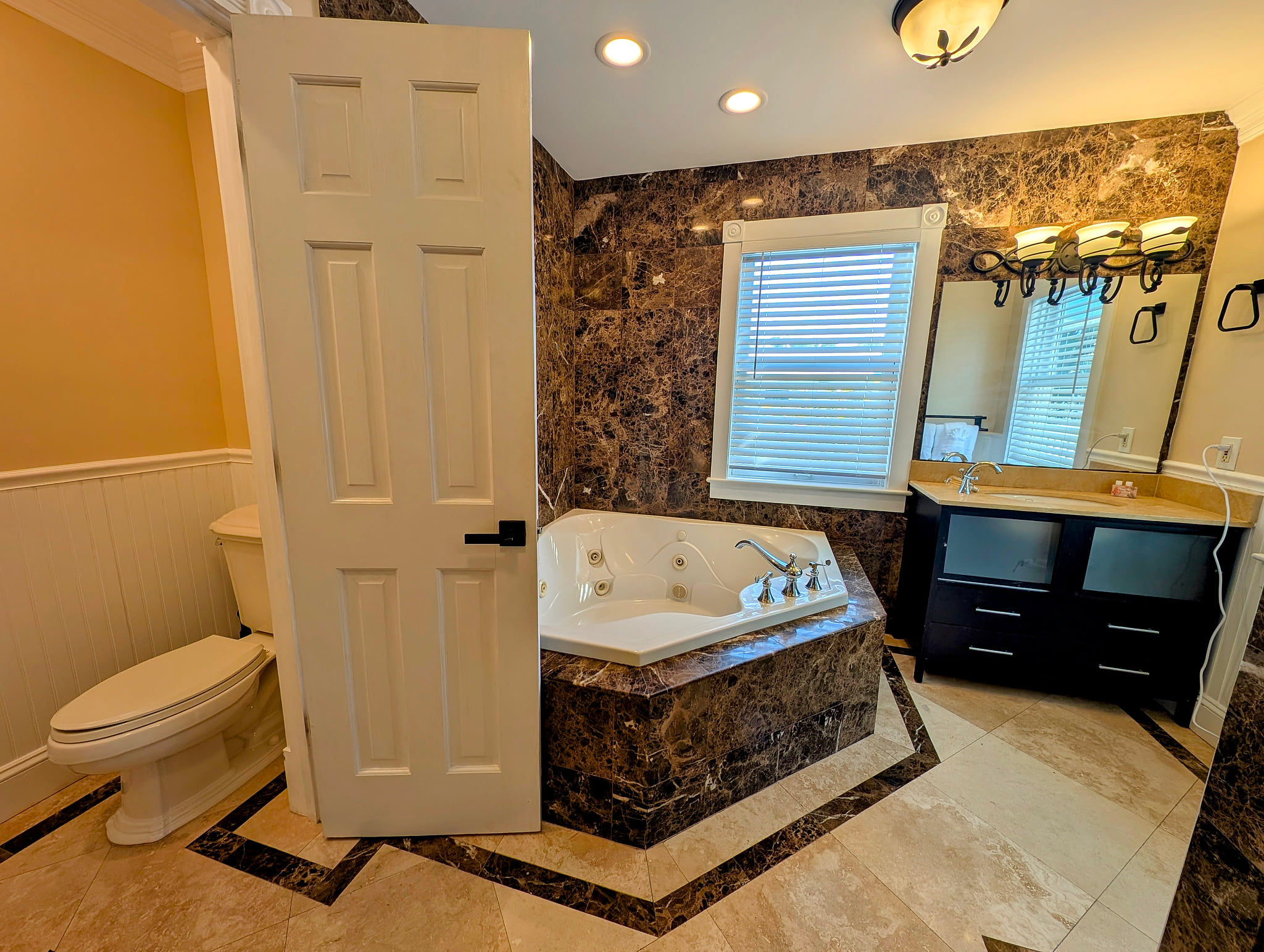 Spa-like tub, marble tile, and bright vanity.