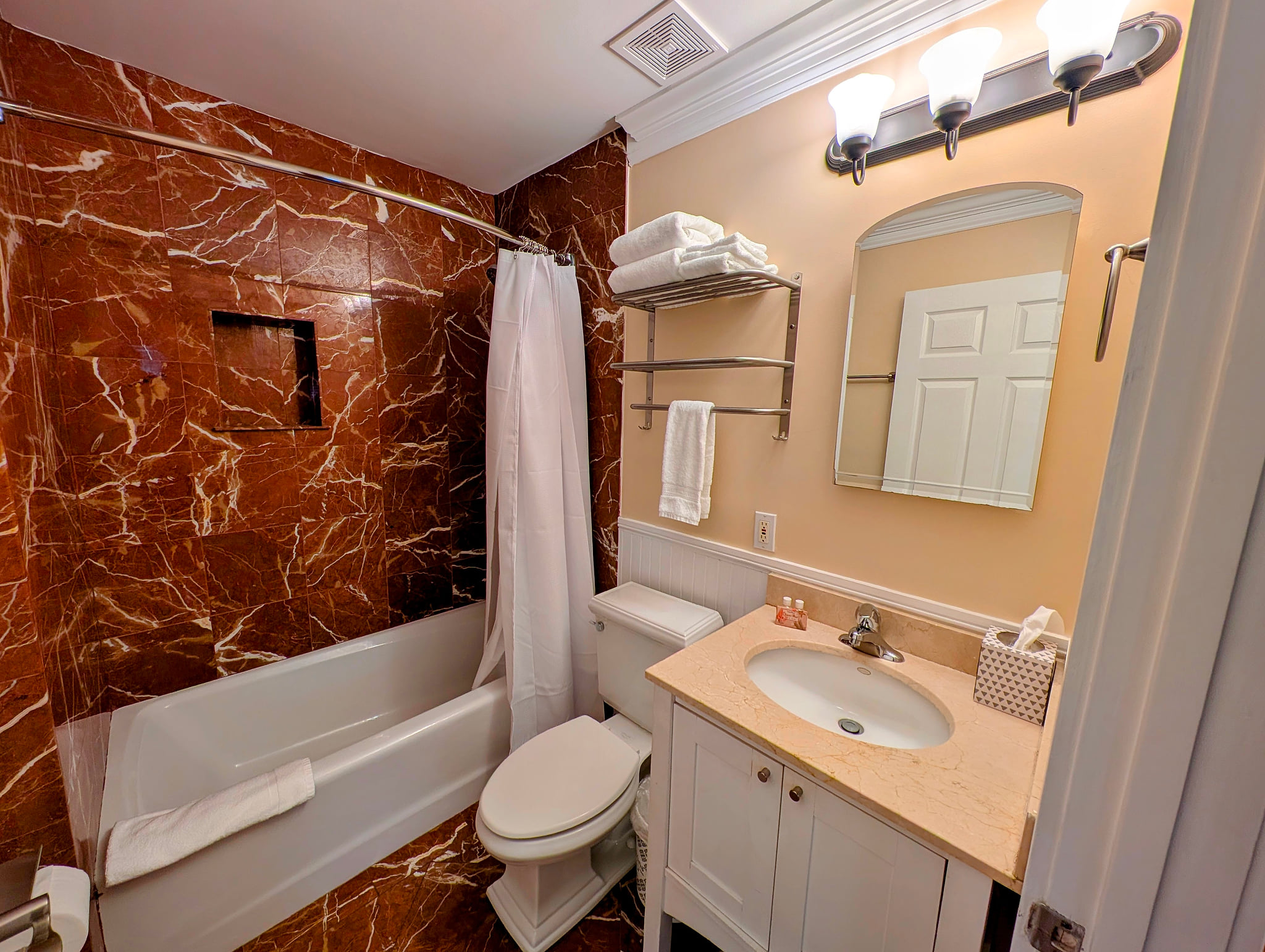 First floor elegant marble-tiled bath with soaking tub, fresh towels, and essentials