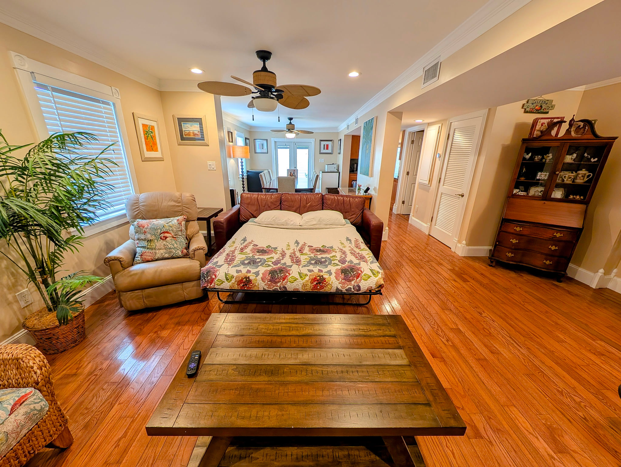 Bright lounge with sleeper sofa, hardwood floors, and ceiling fans.