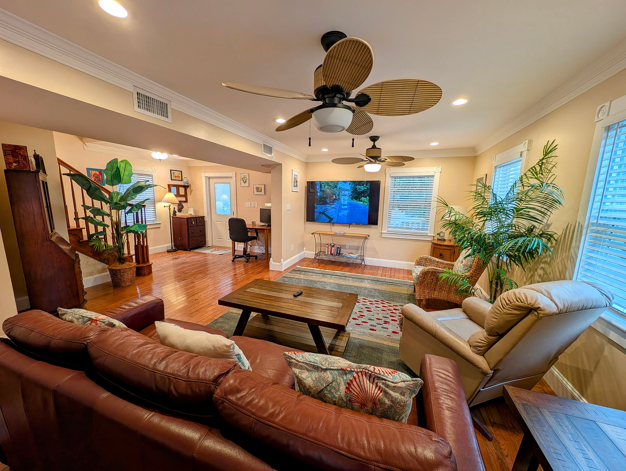Bright living room with large 75 inch smart TV, leather sofa, recliner & workspace