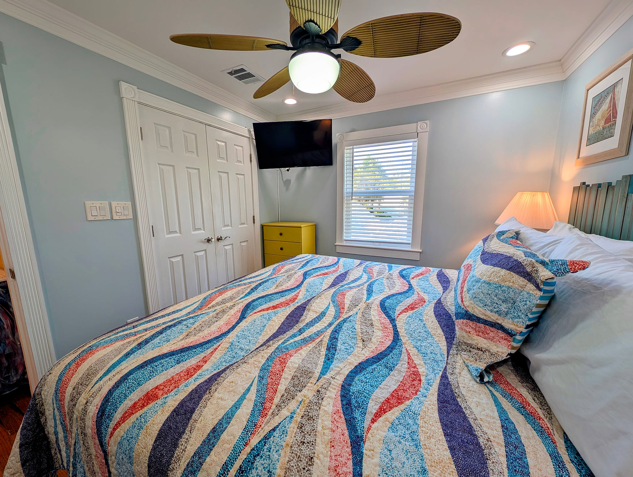 Cozy coastal bedroom with king bed, 42 inch smart TV, fan, and ample storage.