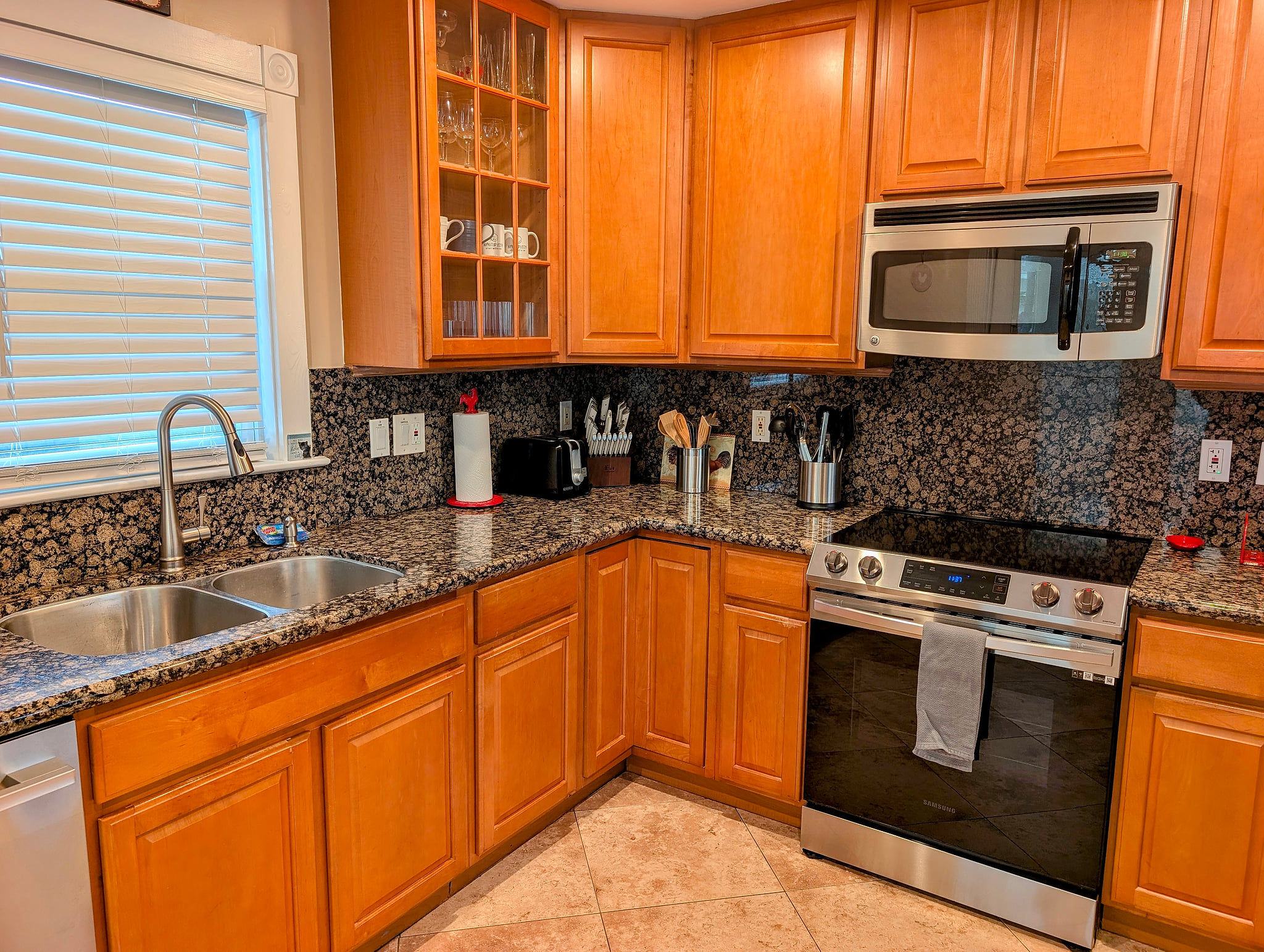 Granite kitchen with stainless range, microwave, and fully stocked tools