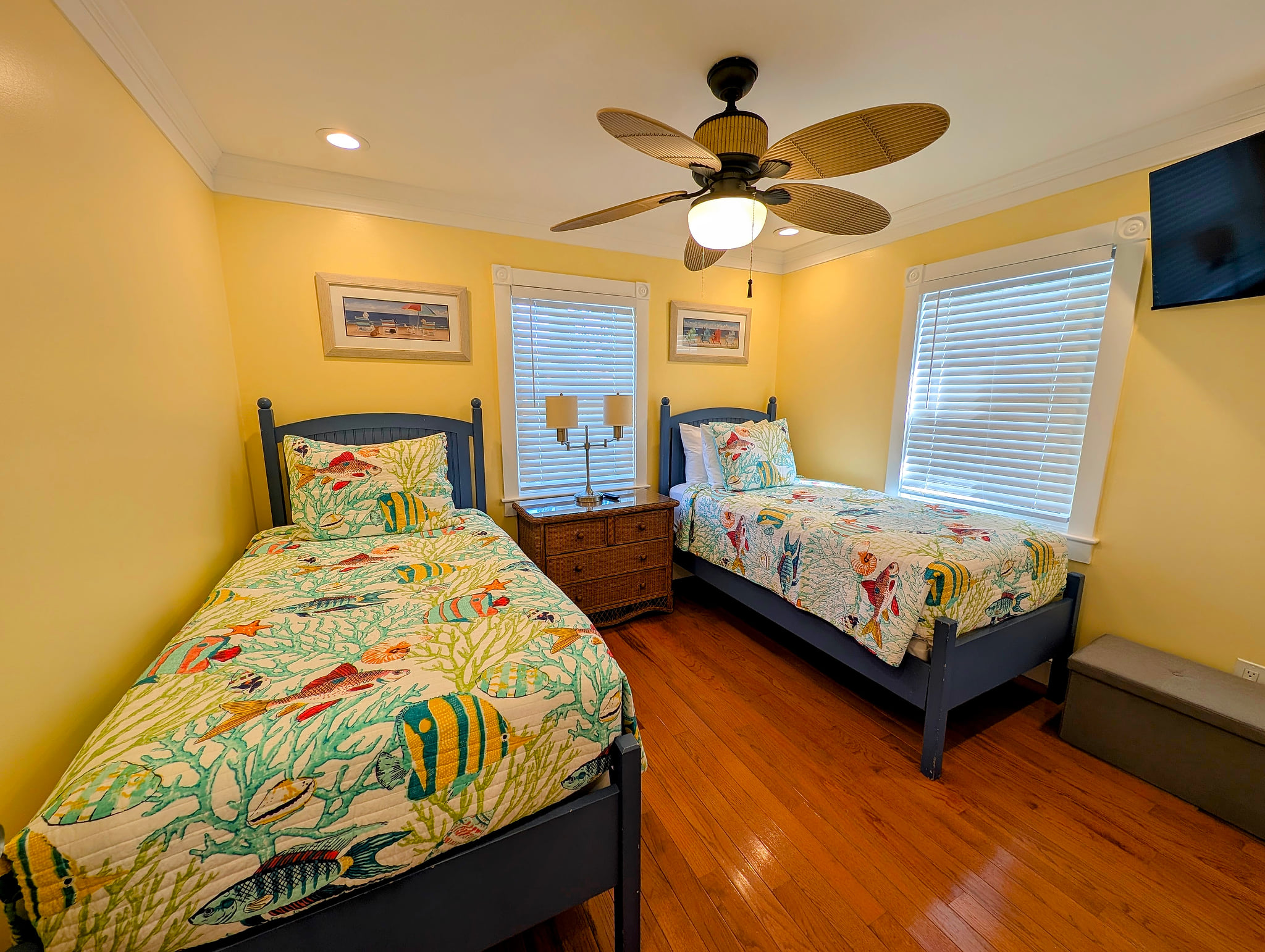 Bright twin room with coastal decor, ceiling fan, 40 inch smart TV & hardwood floors.