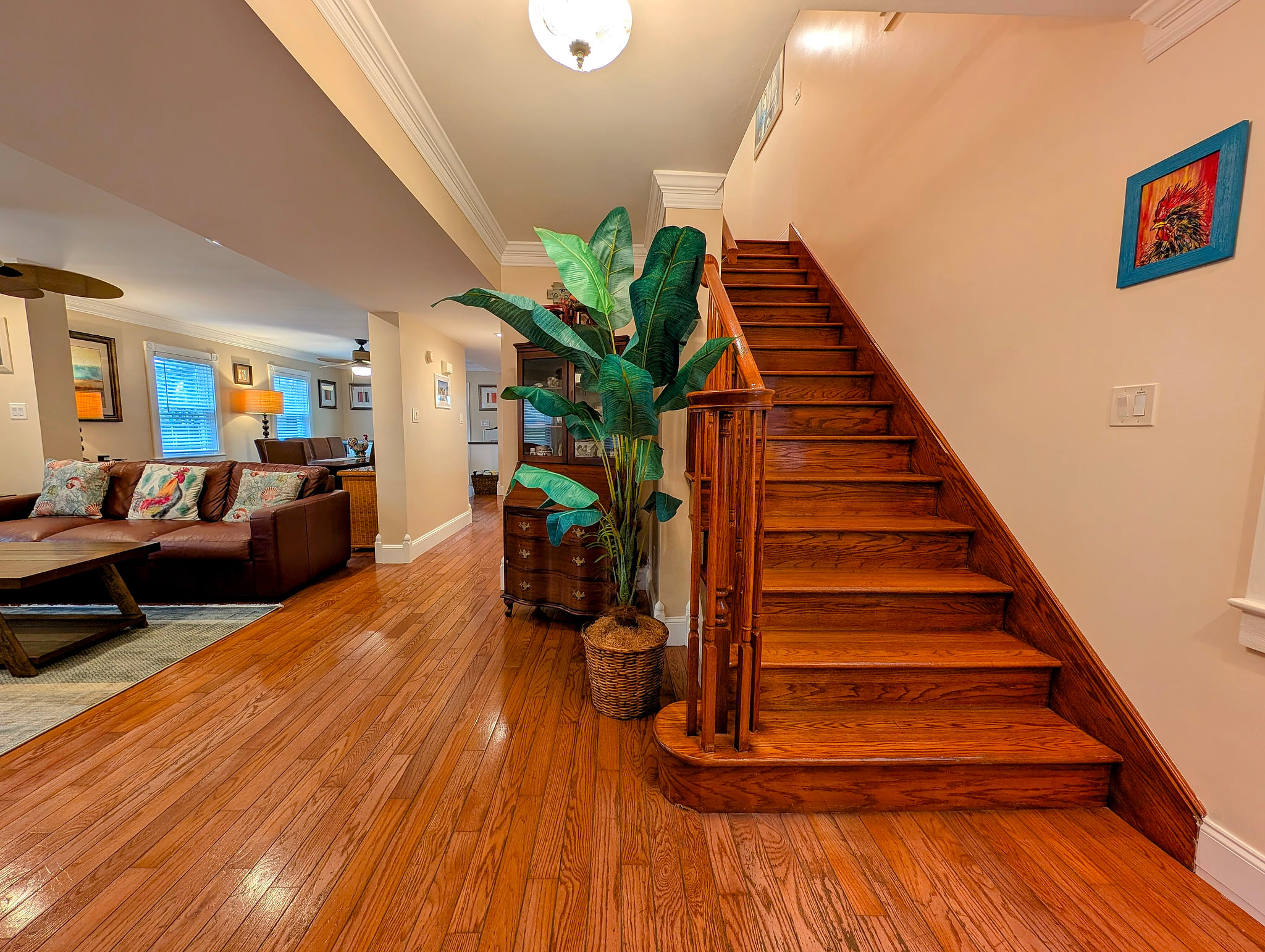 Warm hardwood entry with open living room and classic wood stairs