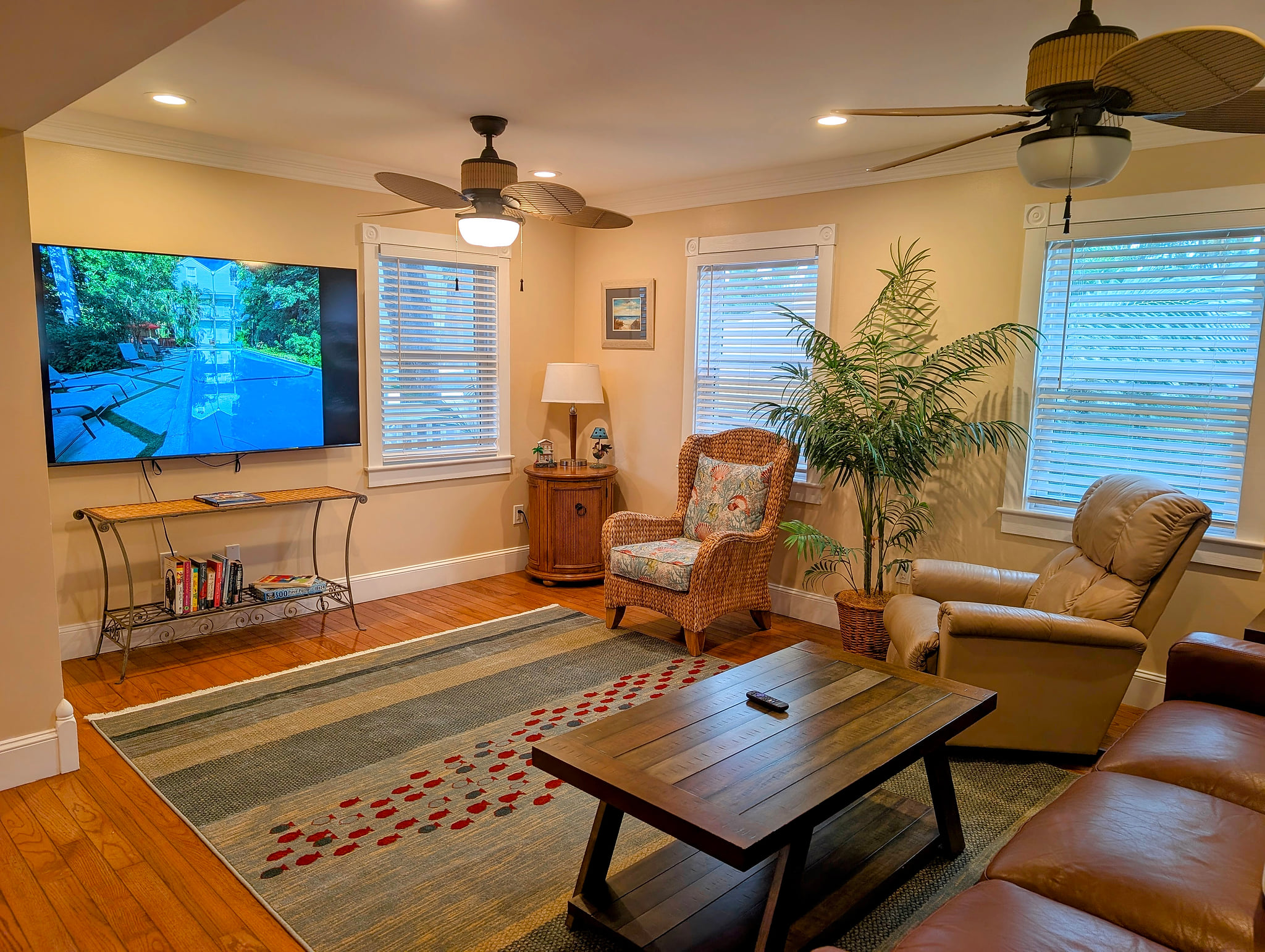 Bright living room with large 75 inch smart TV, comfy seating & ceiling fans