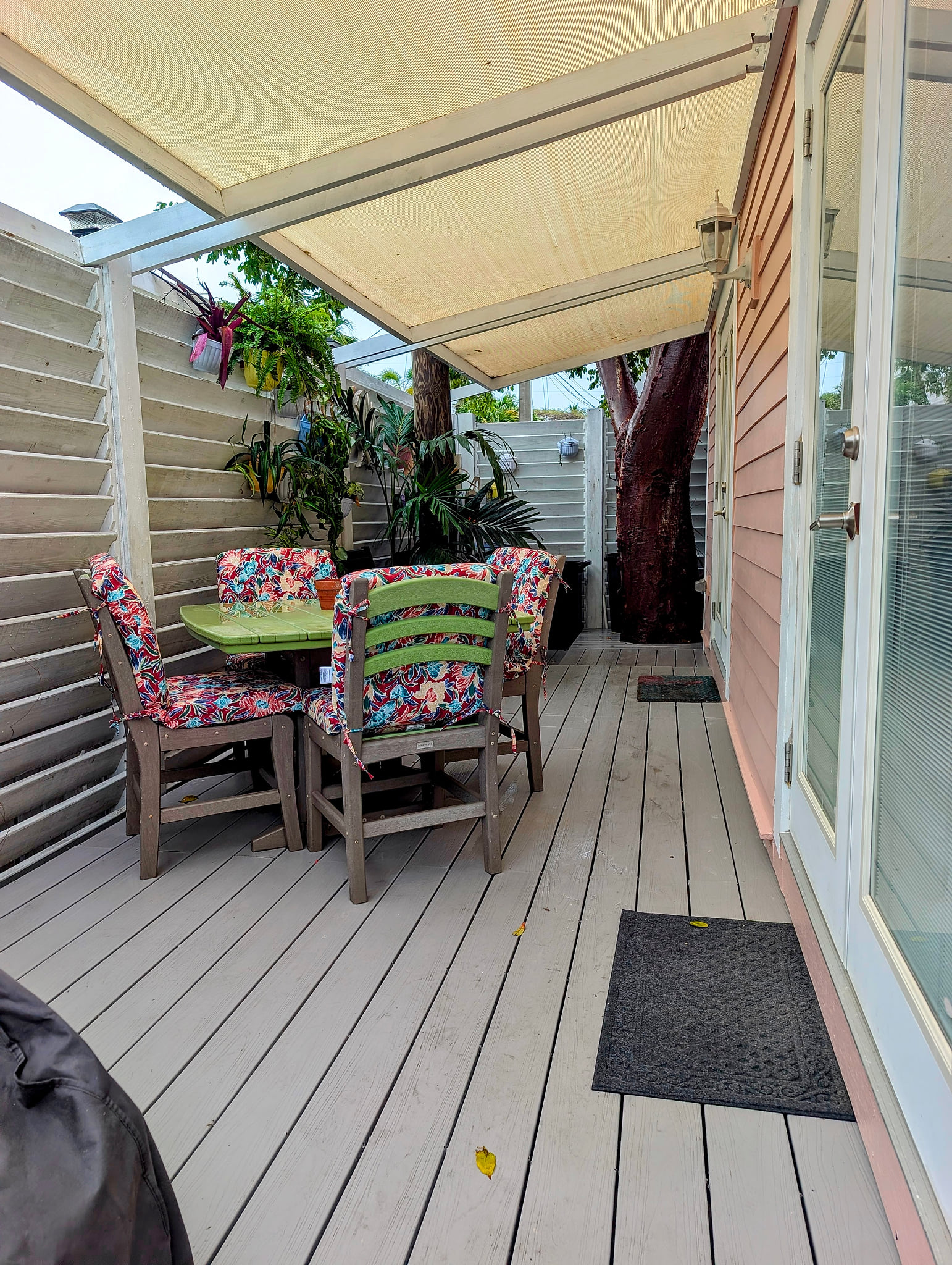 Private shaded deck with colorful dining set and lush greenery