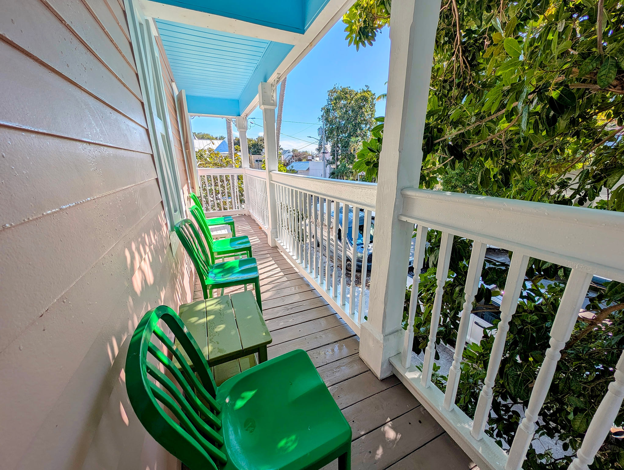 Second floor shaded balcony with seating and leafy street views—perfect to unwind.