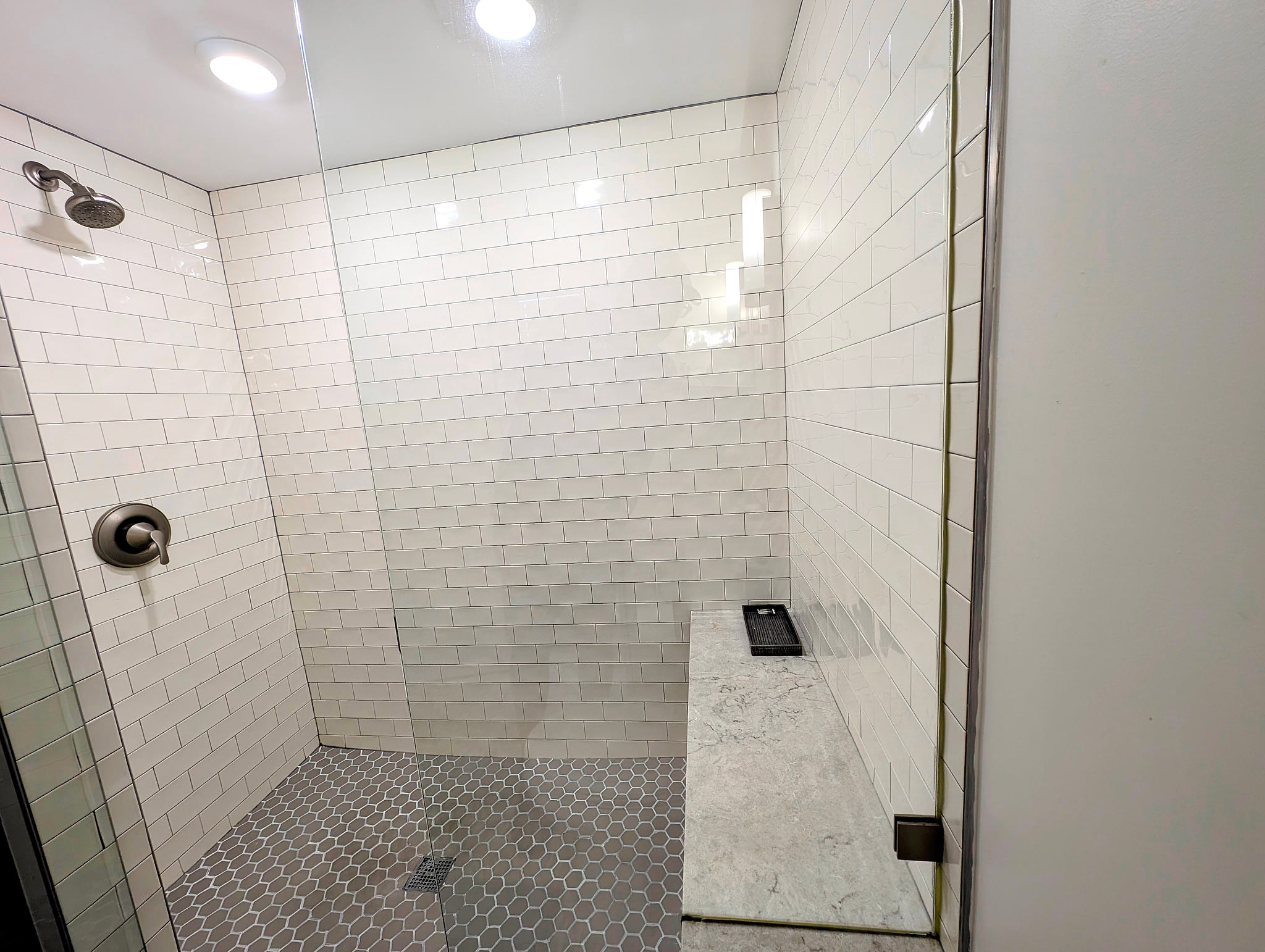Spacious walk-in shower with bench, niche, and chic subway tile.