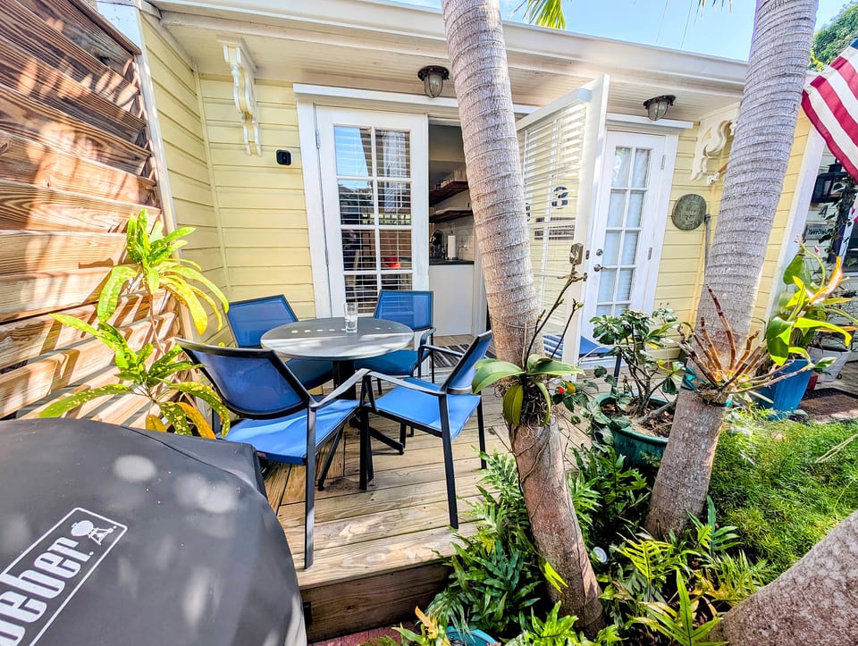 Sunny tropical patio with bistro set, grill & French doors