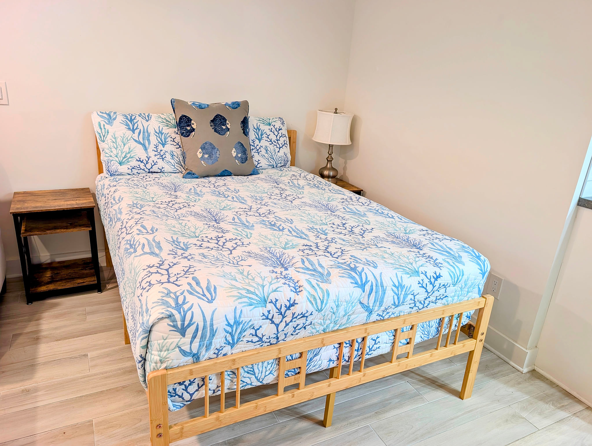 Bright coastal bedroom with comfy bed, nightstands, and warm lamp.