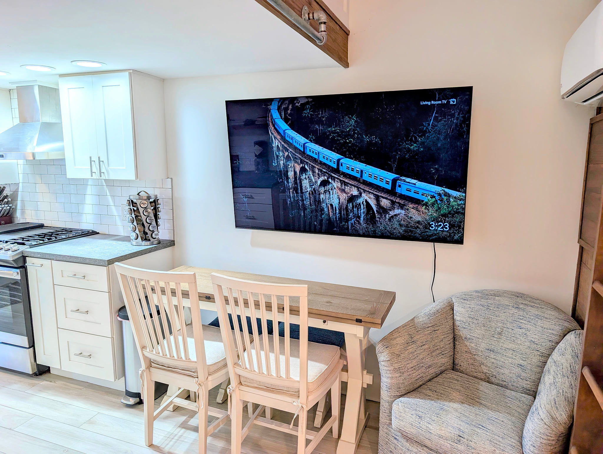 Bright kitchen with large smart TV, dining/work nook, and cozy chair