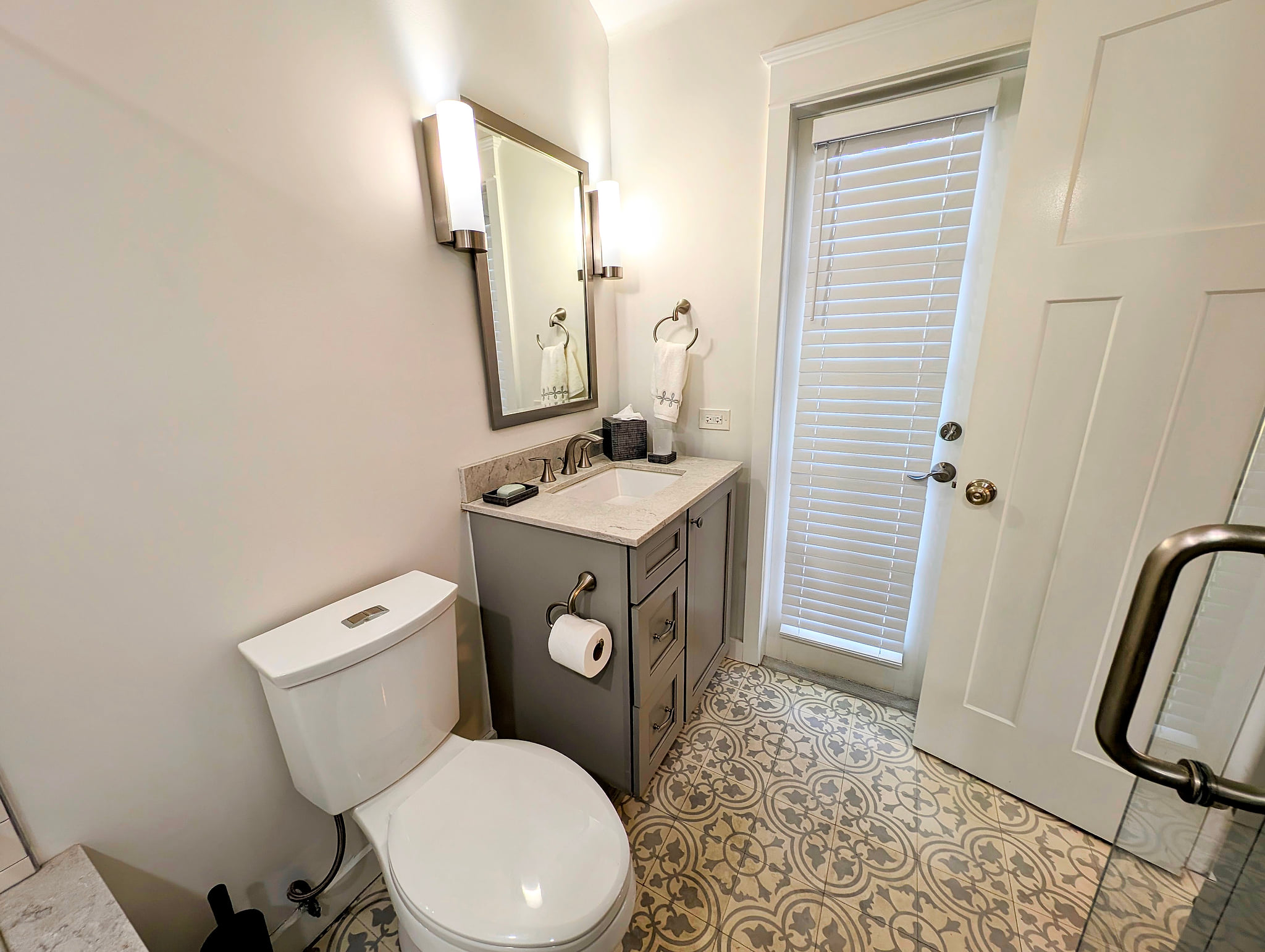 Bright bath with patterned tile, glass shower, and light-filled door