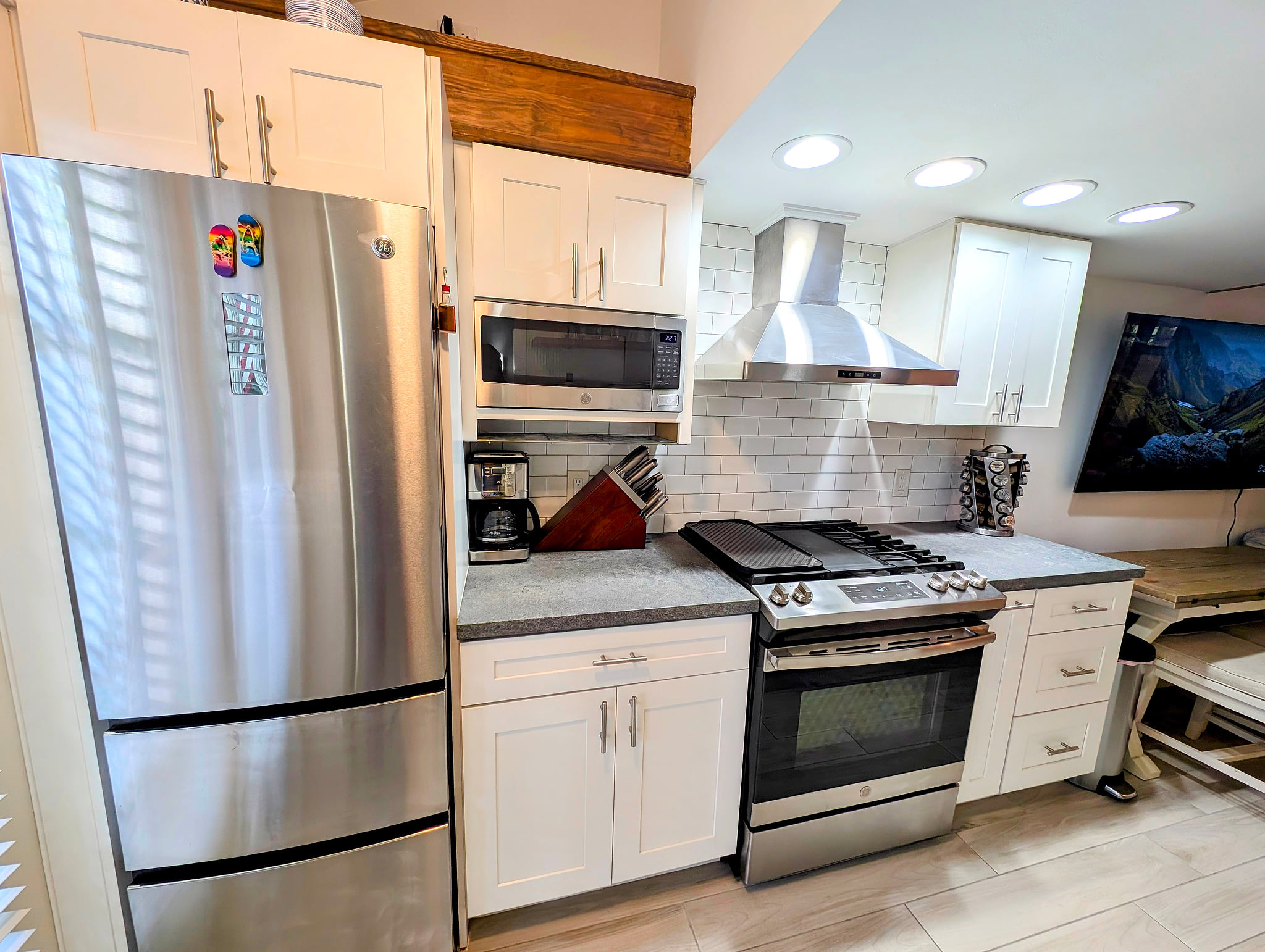 Modern kitchen: stainless appliances, gas range, hood, and coffee station.