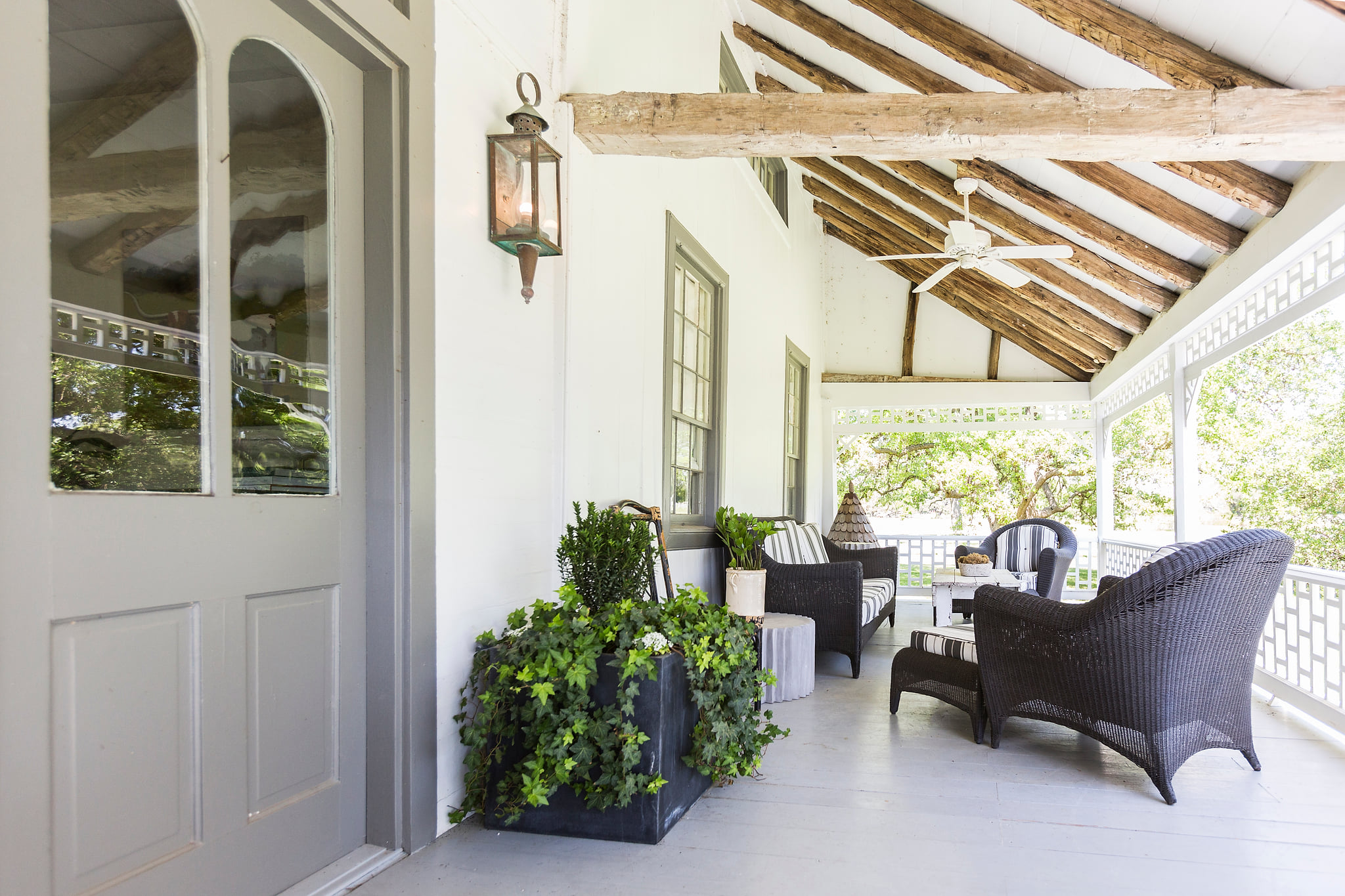 Shaded porch with wicker seating, beams, and leafy treetop views