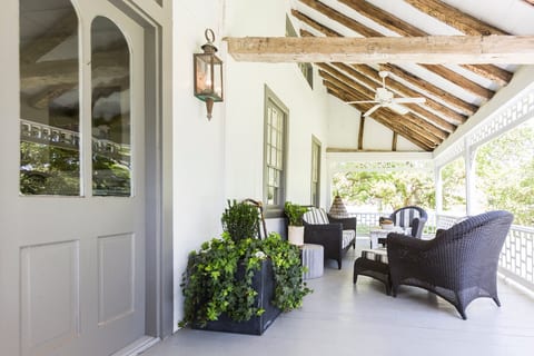 Shaded porch with wicker seating, beams, and leafy treetop views