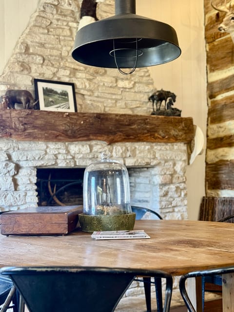 Cozy cabin dining nook with stone fireplace and industrial pendant