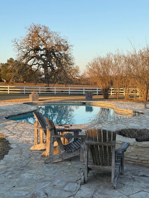 Rustic pool retreat with fire pit and wide-open ranch views at sunset