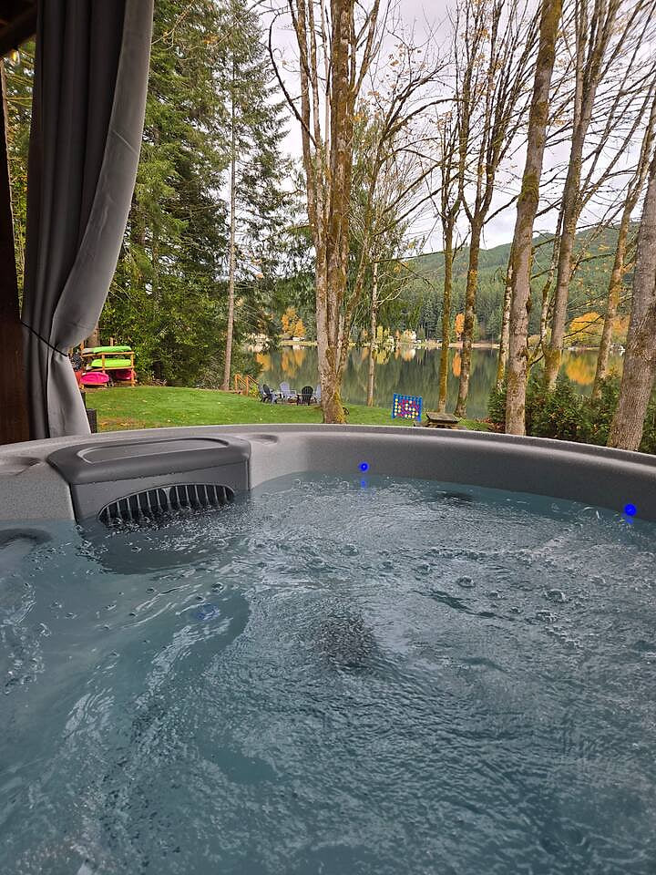 Relax in the private hot tub with serene lake views.