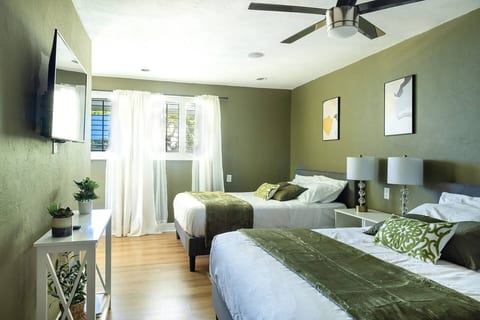 sage green bedroom with 2 queen beds and entertainment