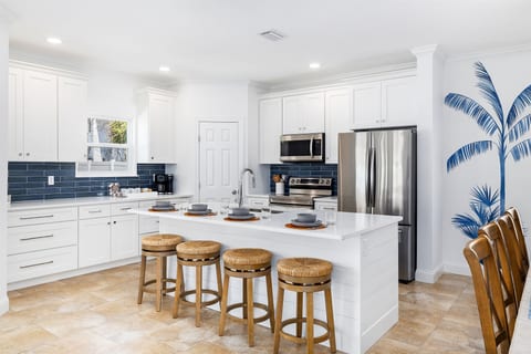 Beautifully renovated kitchen featuring quartz countertops, stainless steel appliances, and a spacious island with seating for four — ideal for gathering, cooking, and casual meals.