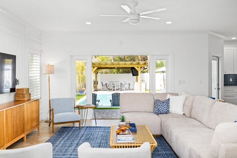 Bright, open living space with comfortable seating and large sliding doors that open directly to the backyard pool area — perfect for indoor-outdoor coastal living.