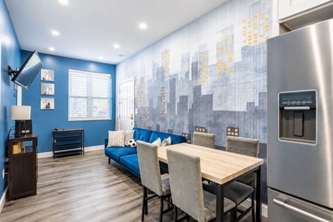 Bright dining and lounge area with seating for six, comfortable sofa, and modern city-inspired décor.