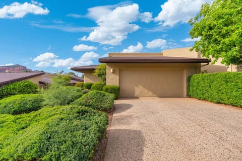 Clean and welcoming home exterior featuring a red tile roof and classic Southwestern architecture. The neatly landscaped front yard with desert plants and a paved walkway creates a charming first impression for your Sedona getaway.