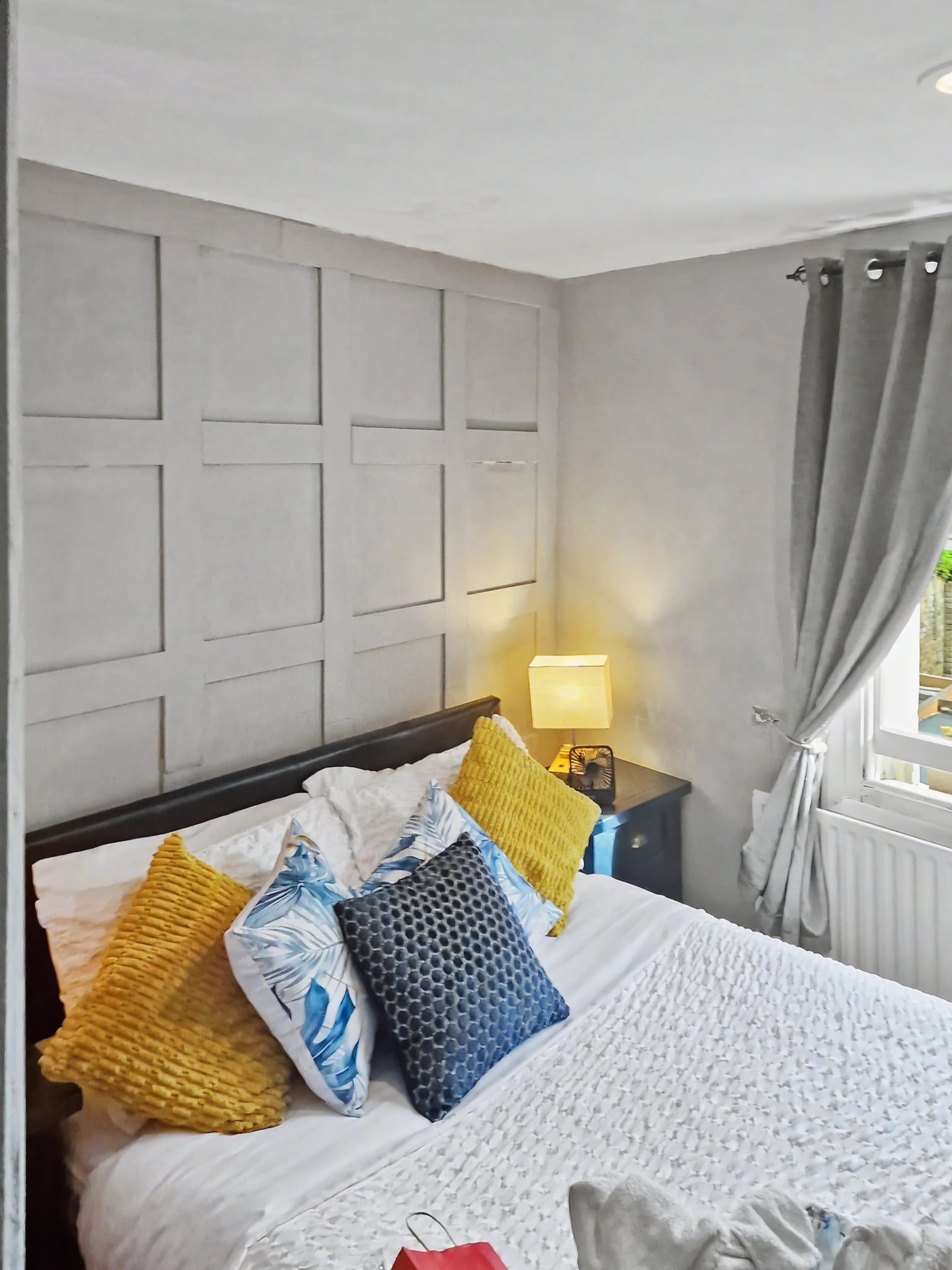 Cozy double room with paneled accent wall and sunlit window