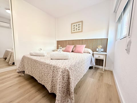 Sunny, stylish bedroom with queen bed, AC, wood floors, and mirrored closet.