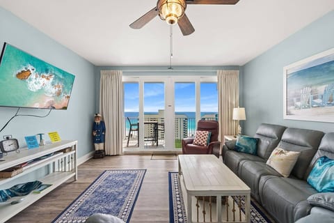 Coastal living space featuring Smart TV, cozy seating, and stunning ocean views through floor-to-ceiling doors.