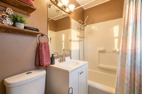 Bright full bath with tub/shower, warm lighting, and stylish shelf accents
