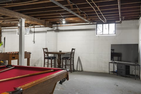 Unfinished basement game room w/ pool, foosball, TV & pub table