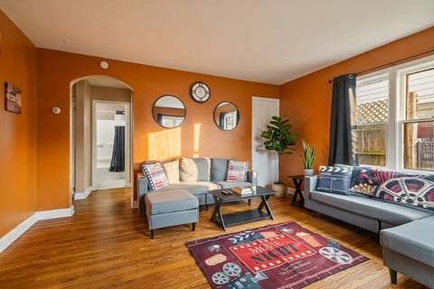 Sunny, stylish living room with hardwood floors and cozy seating