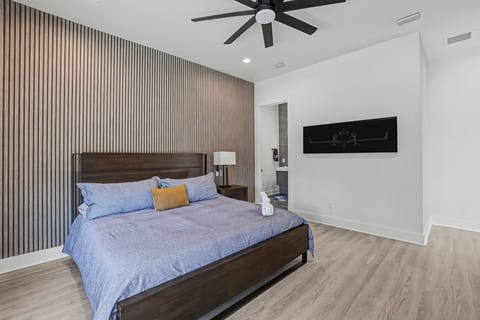 Sleek king suite with slat accent wall, fan, and en‑suite bath