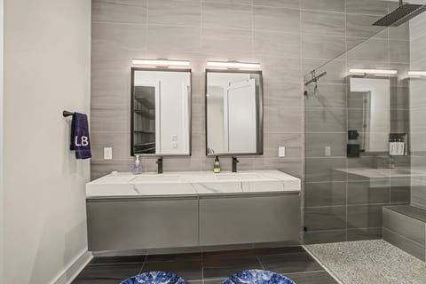 Sleek spa bathroom with double vanity, LED mirrors, and rainfall shower.
