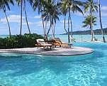 Tropical lagoon pool with sun loungers and sweeping ocean views